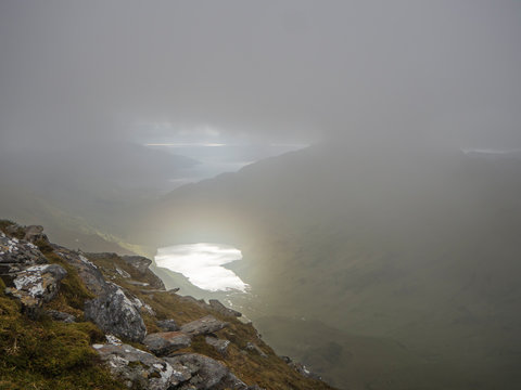 High angle view of lake amidst mountains against cloudy sky during foggy weather, Scotland, UK
