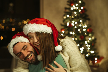 Fototapeta na wymiar christmas couple hugs and laughting with santa claus hat; xmas celebraiting concept
