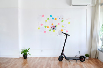 Electric scooter in front of a wall full of sticky notes in a bright modern office