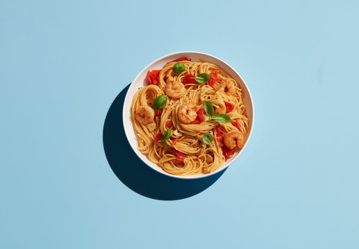 Directly above shot of shrimp pasta in bowl on blue background