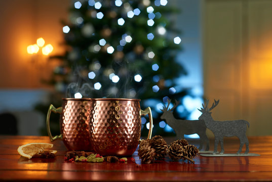 Close-up of mulled wine with food and decorations on table against illuminated Christmas tree at home