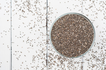 Chia seeds in a bowl on a white wooden background