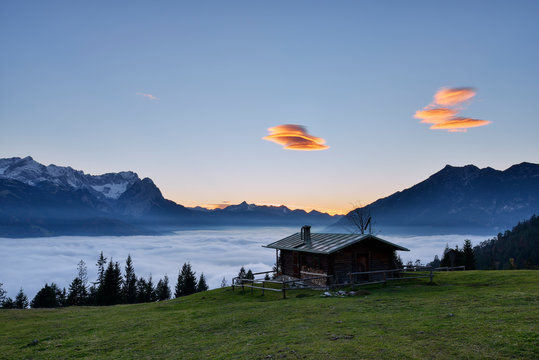 Log cabin at Mt. Wank with beautiful Mount Zugspitze and cloudscape in background at night, Bavaria, Germany
