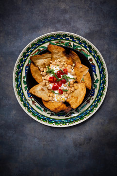 Bowl of Levantine fatteh, with flat bread, tomatoes and chickpeas