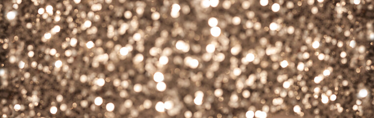 Gold glittering blurred lights banner with empty space. Christmas New Year abstract background for design.