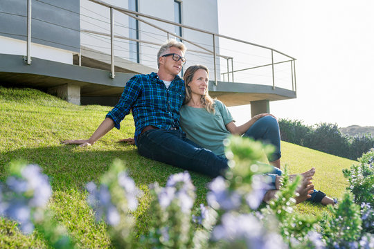 Smiling couple stitting in front of their modern home