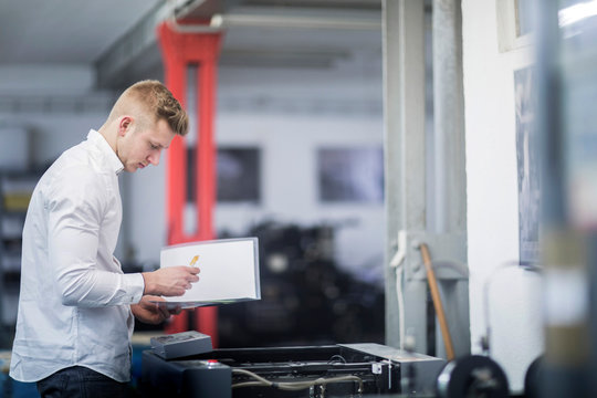 Young man checking printer in a printing company