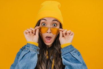 Close up of surprised asian woman in yellow hat and sunglasses looking excitement