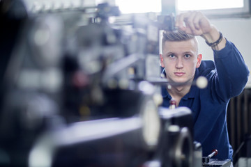 Young man adjusting a machine in a printing company