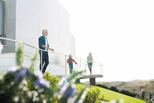 Casual man with his family standing in front of modern home looking at the landscape