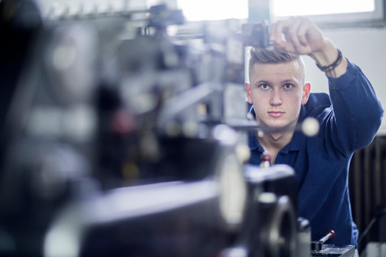 Young man adjusting a machine in a printing company