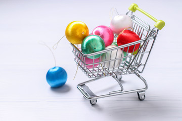 Trolley cart and colorful new year balls on white background, creative flat lay shopping, Copy space