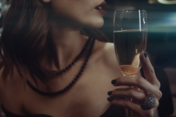 woman holds glass of champagne near lips.