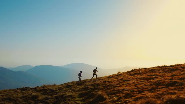 Aerial shot of a woman and a man running together in the hills