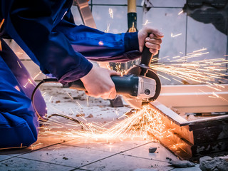 craftswoman using angle grinder to cut old door frame with sparks flying around