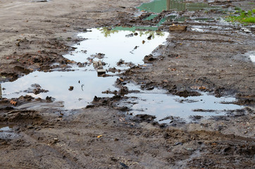 A dirt road with mud and puddles, the first frosts, problem roads in the countryside.
