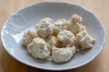 Coconuts made of egg whites, sugar and shredded coconut on white plate on wooden table, group of Christmas sweets
