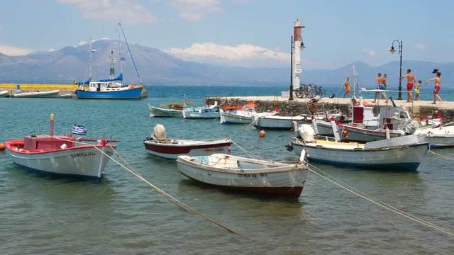 The fishing boats are moored in the open sea near old pier on a sunny summer day close-up (Greece). Travel to Europe. Traveling concept.