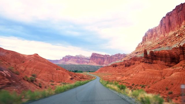 Scenic drive road in Capitol Reef National Monument panning point of view of colorful stone red rock in Utah 