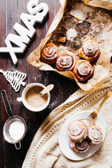 Drinking  cofee and eating cinnamon  rolls circled by christmas decoration,.