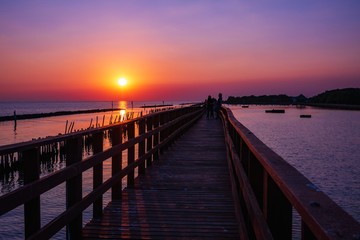 Fototapeta na wymiar wooden pier at the sea with beautiful bloody sunset. sunset seascape at a wooden jetty. Wood bridge