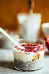 Chia parfait yogurt dessert with cereals and pomegranate seeds on a rustic environment