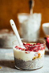Chia parfait yogurt dessert with cereals and pomegranate seeds on a rustic environment