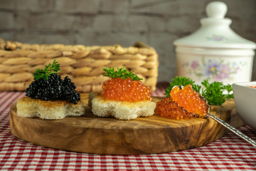 Toasts with red and black caviar on a wooden board