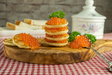 Pancakes with red caviar on a wooden board