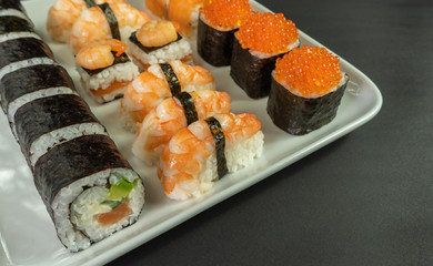 Sushi and rolls with red caviar and shrimp on a white dish