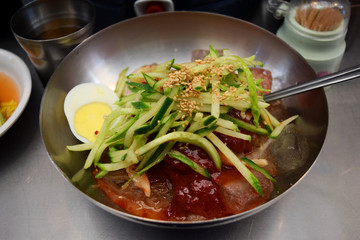 Spicy Korean cold noodles (naengmyeon) with vegetables and egg in a steel bowl, Seoul, South Korea