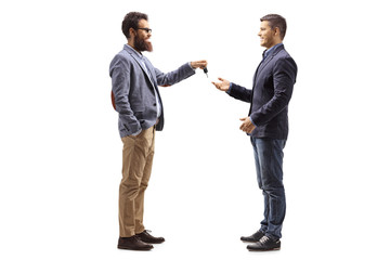 Bearded man giving car keys to a young man