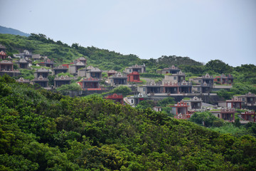 Fototapeta premium Taiwanese cemetery on a cliffside within a forest, with colorful shrines, Taipei, Taiwan