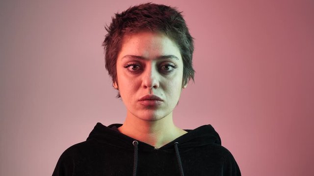 Portrait of a short-haired teenager girl in neon rays. The girl looks directly at the camera, touches hair. 4k