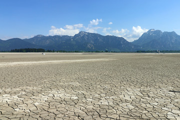 Ein Stand Up Paddler sucht auf einem ausgetrockneten See nach Wasser. Der ausgetrocknete Forggensee...
