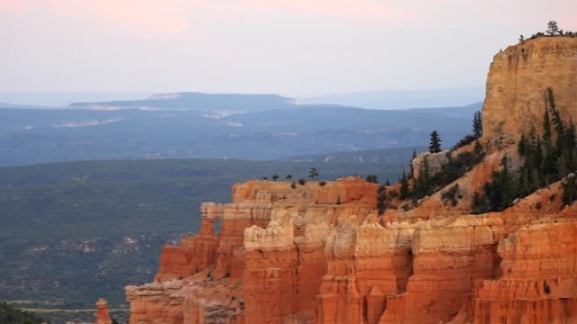 Paria view overlook panning zooming out on orange pink cliff rock hoodoos in Bryce Canyon National Park in Utah at dark sunset twilight and sunlight on formation