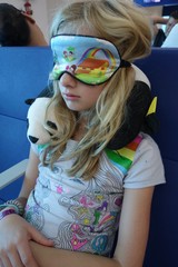 Portrait of a girl resting at an airport with an eye mask and neck pillow