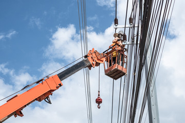 Two electrician workers are climbing on the electric poles to install and repair power lines.
