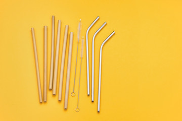 Reusable cocktail straws and cleaning brush on yellow background. Zero waste concept.