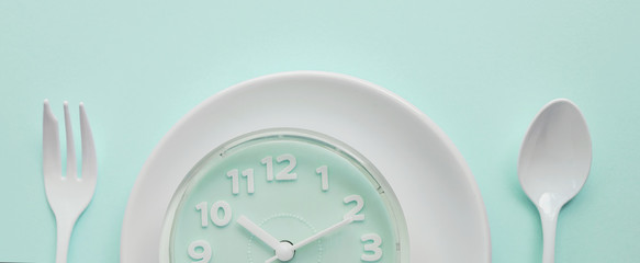 blue clock on white plate with fork and spoon, Intermittent fasting concept, ketogenic diet, weight...