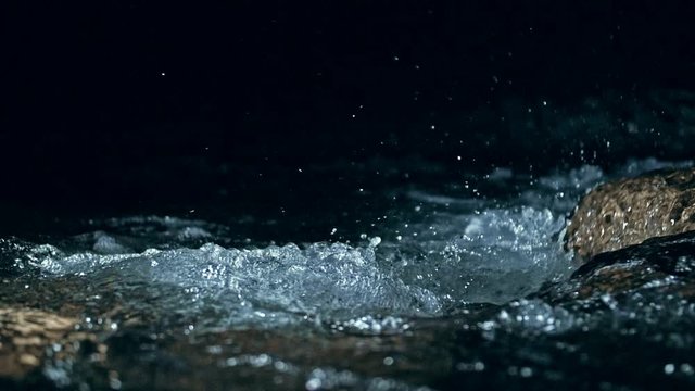 Slow motion of waves on dark water surface with play of flecks of bright light close up. Amazing dramatic natural background. Shooting with 180fps. Epic mystical and magic night view. Crystal clear