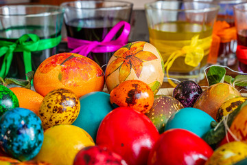 Fototapeta na wymiar Close up photo of colorful easter quail egg and glasses of paint with ribbon.