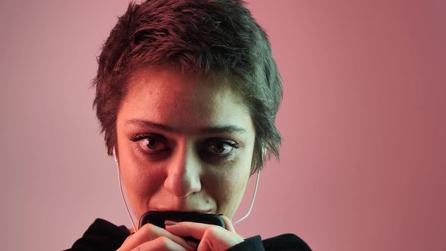 a short-haired girl is waiting for a message. She put the phone to her lips and looks directly at the camera. 4k