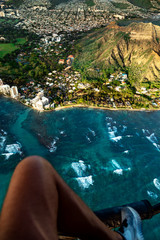 Man's legs during an off-door helicopter flight over Honolulu, Oahu, Hawaii. Man watching the city from the sky. Perfect summer and sunset time.