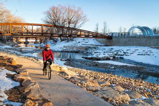 senior male cyclist is riding a bike in winter sunset scenery