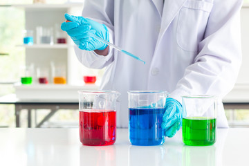 scientist wearing lab coat and gloves taking a sample in syringe while working over scientific experiment in laboratory