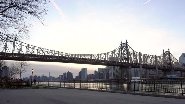 NEW YORK CITY, USA - NOVEMBER 30, 2019 : Couple walking in Queensbridge park with Ed Koch Queensboro Bridge view in the evening