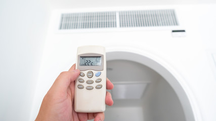 Air conditioner inside the room with man open or close remote controller.  Air conditioner with remote controller.