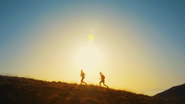 Silhouette of two marathon runners jogging in the hills