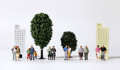 Any of various miniature families standing in front of miniature trees and miniature building.
